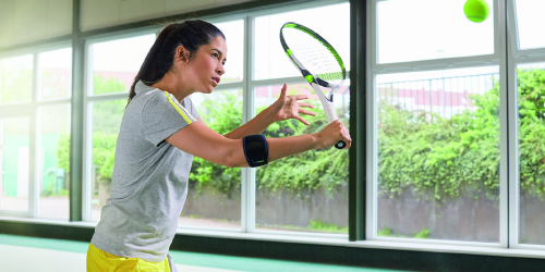 Μια γυναίκα που παίζει τένις φορώντας ένα προϊόν στήριξης αγκώνων Μια γυναίκα που παίζει τένις φορώντας ένα προϊόν στήριξης αγκώνων